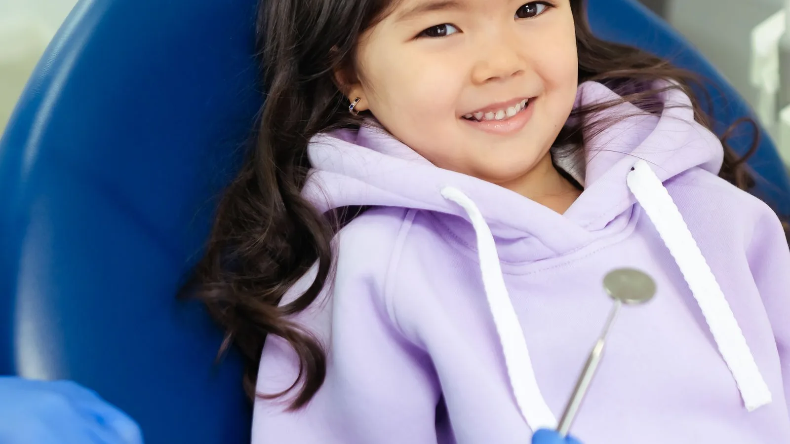 Young girl smiling in a dental chair before her back-to-school checkup