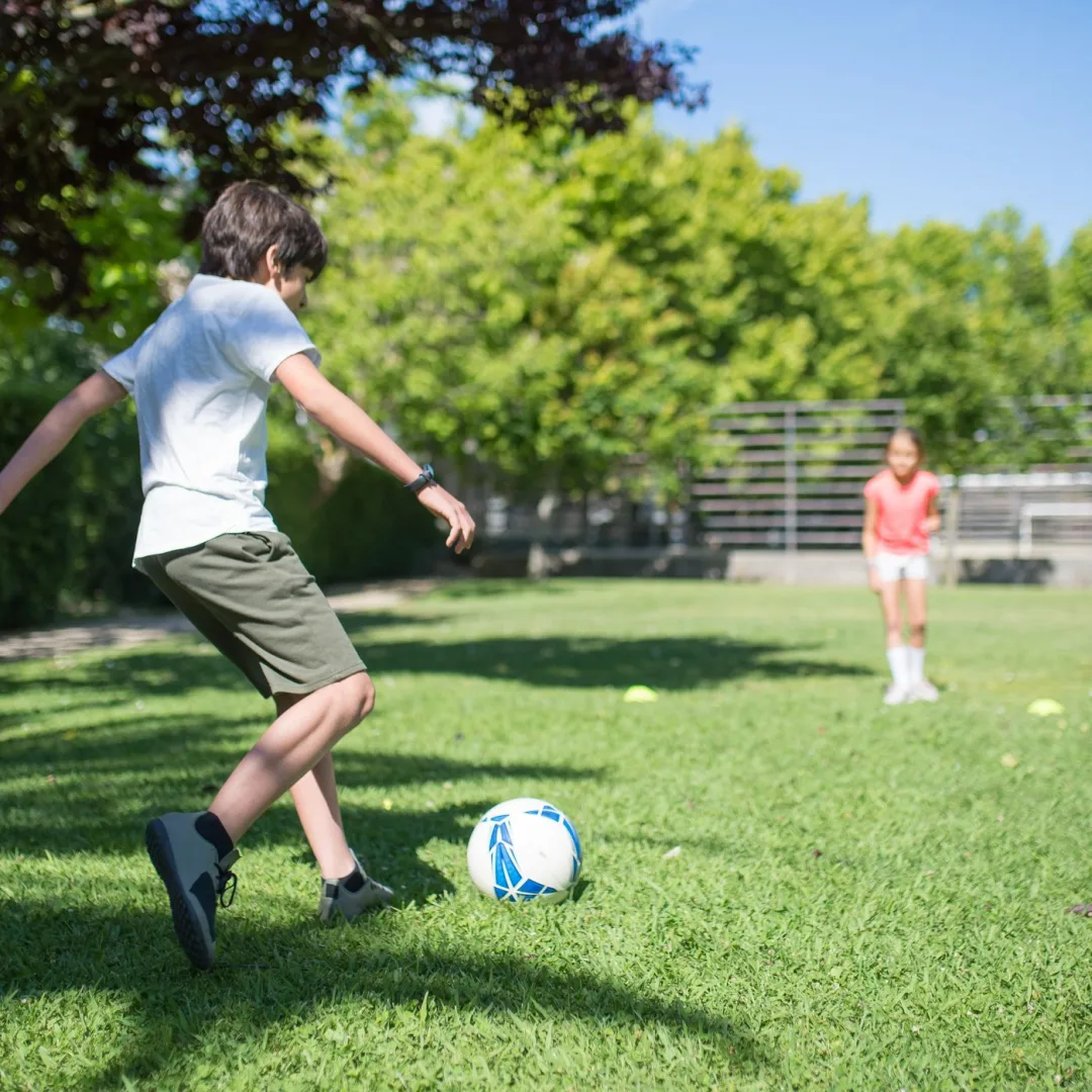 Kids playing soccer outdoors during summer